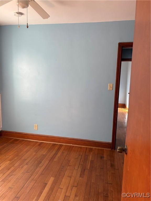 empty room featuring ceiling fan, hardwood / wood-style floors, and baseboards