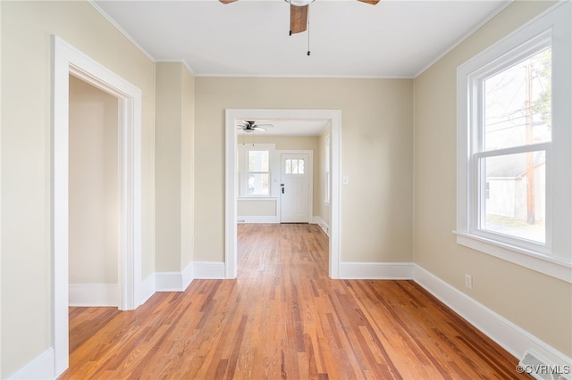 spare room featuring light wood-style flooring, visible vents, baseboards, and ornamental molding