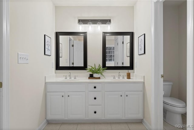 full bathroom featuring double vanity, baseboards, toilet, and a sink