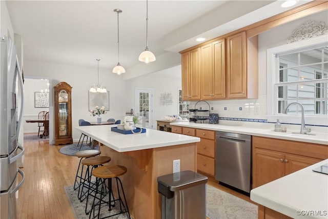 kitchen featuring stainless steel appliances, tasteful backsplash, light wood-style floors, a kitchen island, and a kitchen breakfast bar