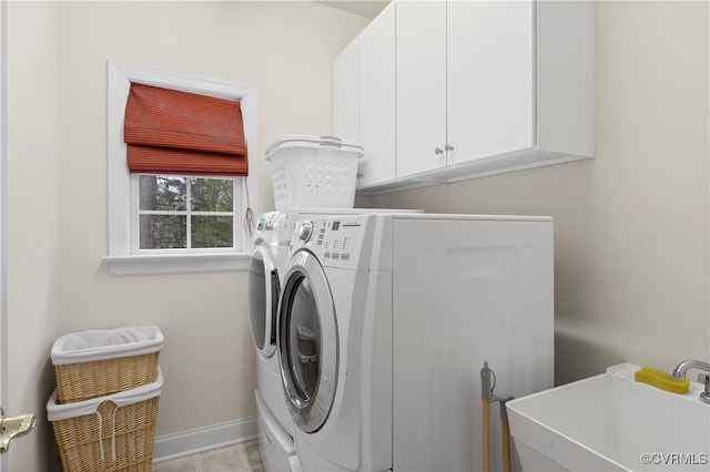 laundry area with washer and dryer, cabinet space, a sink, and baseboards