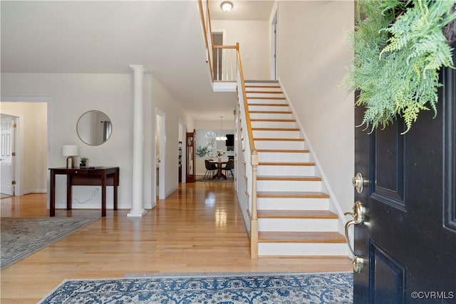 entrance foyer featuring ornate columns, baseboards, stairway, and wood finished floors