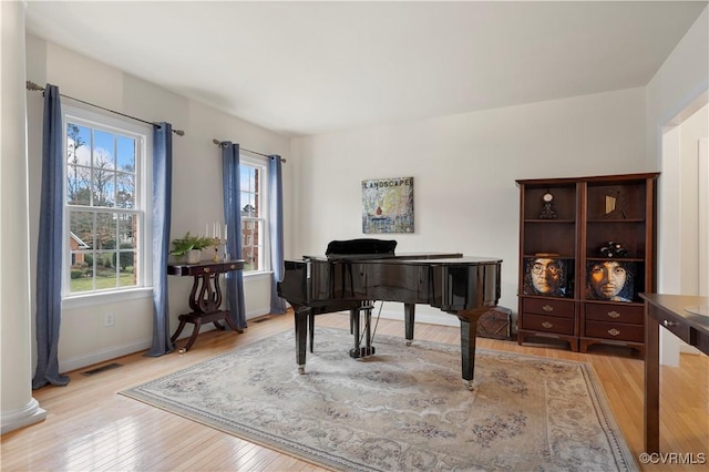 living area featuring light wood-style floors, visible vents, and baseboards