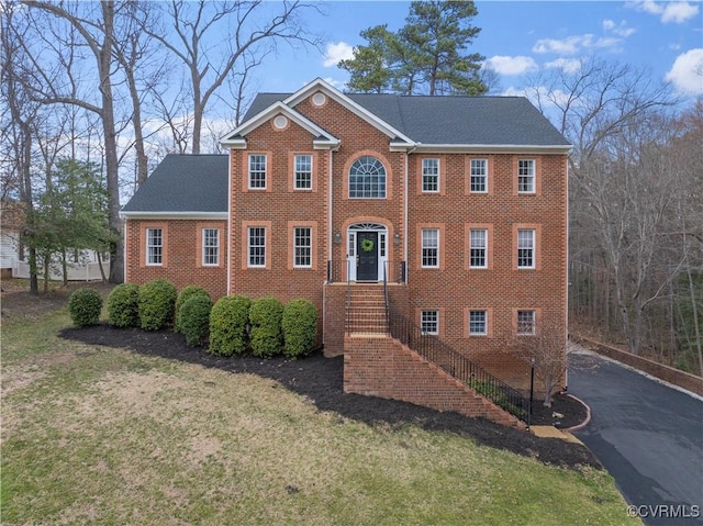 view of front facade featuring a front lawn, aphalt driveway, and brick siding