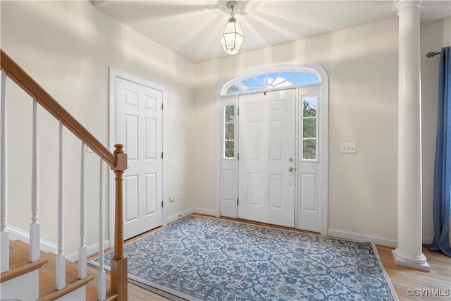 entryway with ornate columns, stairs, baseboards, and light wood-style floors