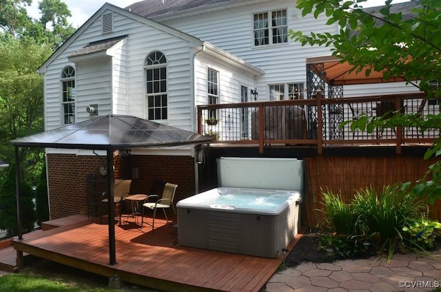 back of property featuring brick siding, a hot tub, and a wooden deck