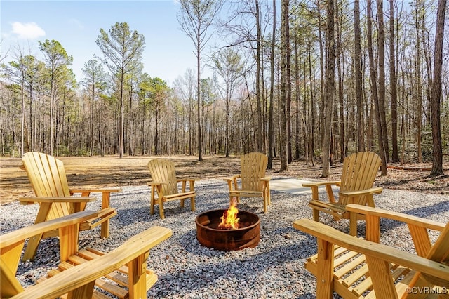 view of patio / terrace with a wooded view and an outdoor fire pit