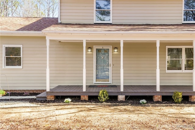 property entrance with covered porch and a shingled roof