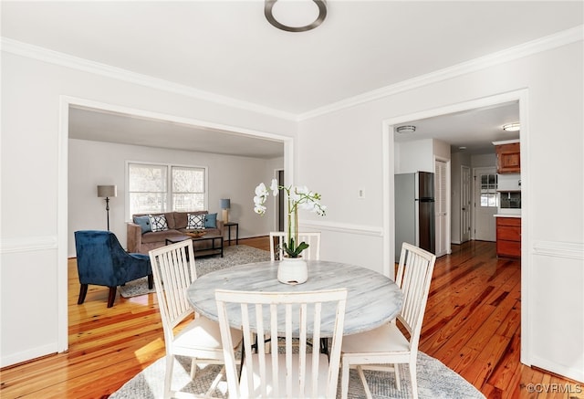 dining space featuring crown molding and light wood finished floors