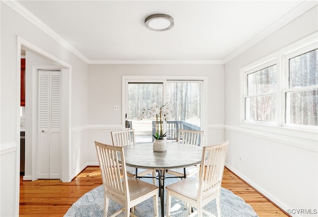 dining area with baseboards, light wood-style flooring, and crown molding