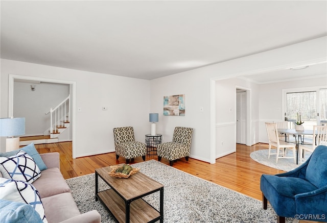 living area with baseboards, wood-type flooring, and stairs