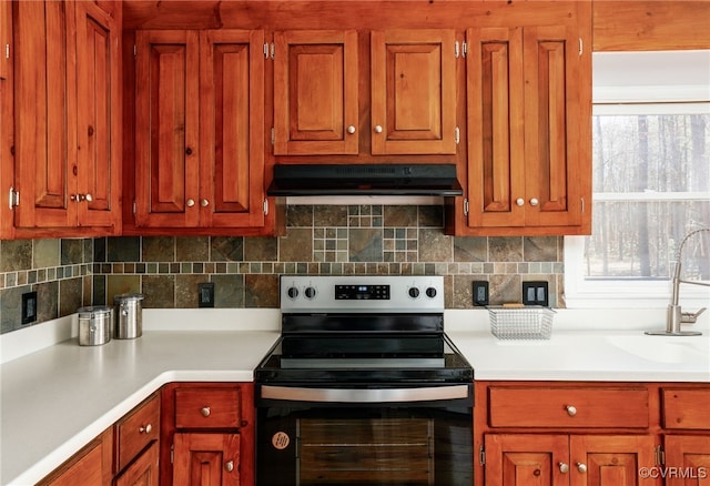 kitchen with light countertops, electric stove, tasteful backsplash, and under cabinet range hood