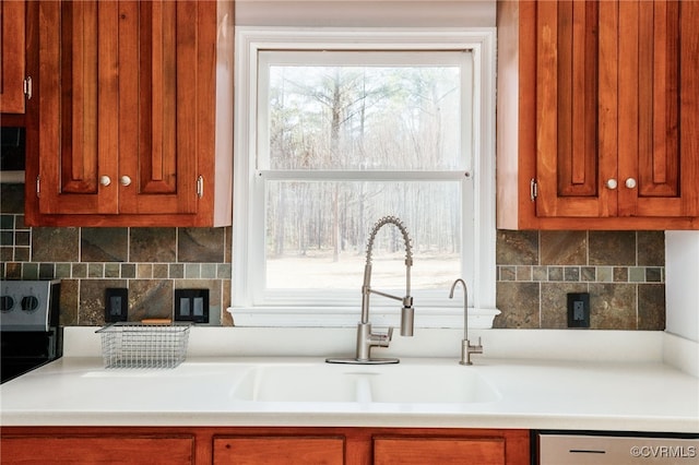 kitchen with tasteful backsplash, dishwashing machine, light countertops, and a sink