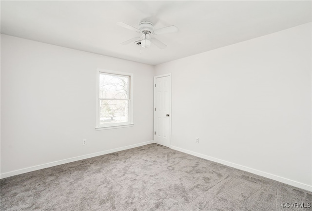 carpeted spare room with baseboards and a ceiling fan