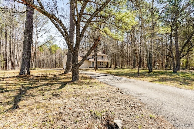 view of street featuring a forest view and aphalt driveway