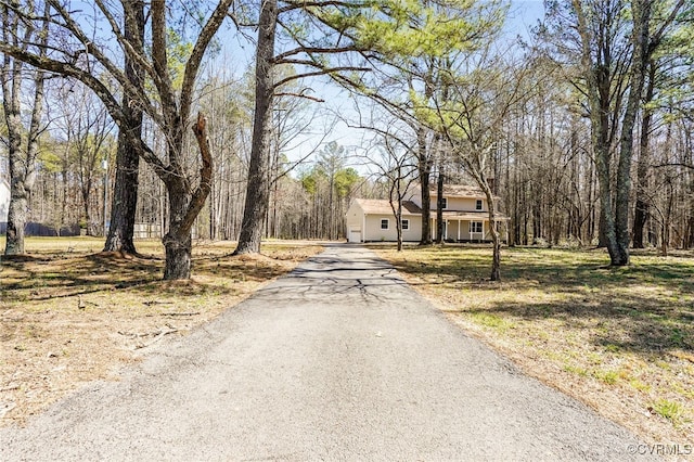 view of road featuring a forest view and driveway