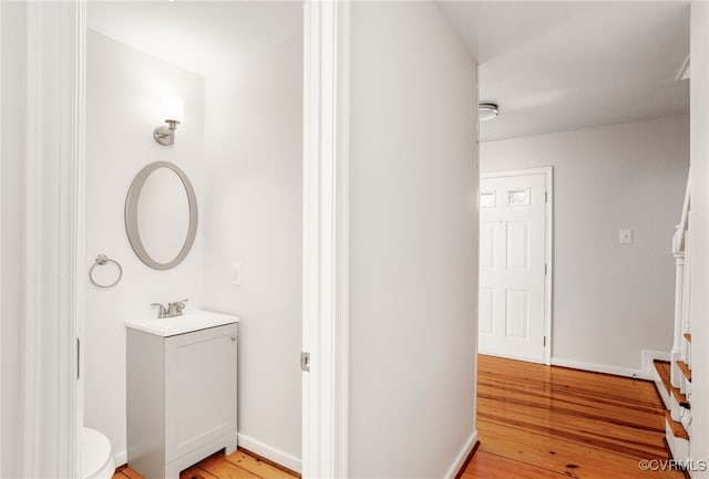 bathroom featuring baseboards, toilet, wood finished floors, and vanity