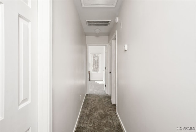 hall with visible vents, attic access, baseboards, and dark colored carpet