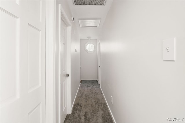 hallway with attic access, baseboards, visible vents, and dark carpet