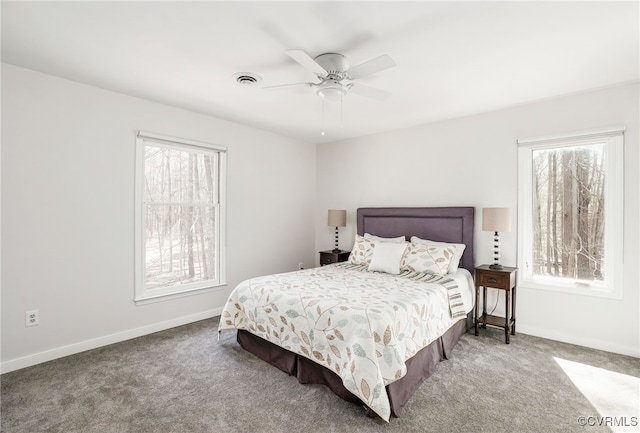 carpeted bedroom with a ceiling fan, multiple windows, baseboards, and visible vents