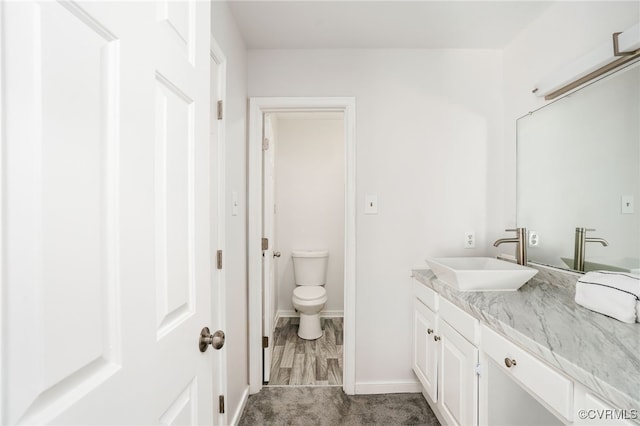 bathroom with vanity, toilet, and baseboards