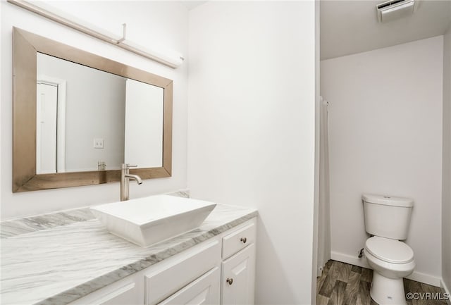 bathroom with visible vents, baseboards, toilet, wood finished floors, and vanity