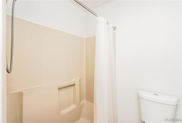 bathroom featuring a shower with shower curtain and toilet