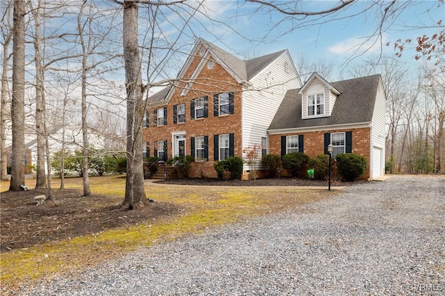 view of front facade featuring a garage, brick siding, driveway, and a shingled roof