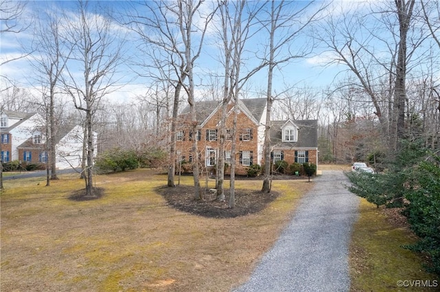 view of front facade with aphalt driveway, brick siding, and a front lawn