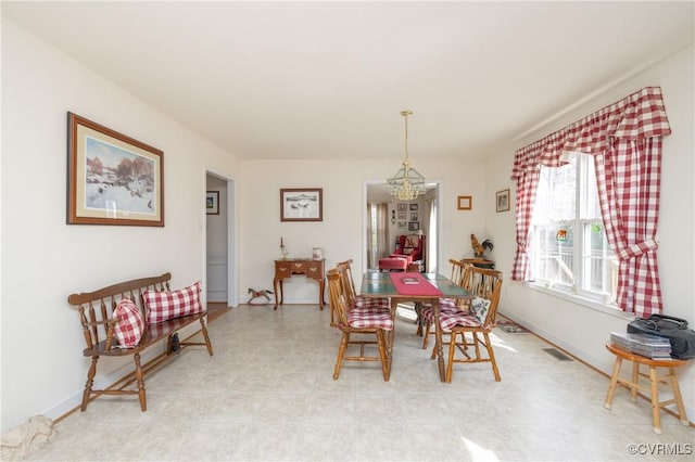 dining area with baseboards, light floors, visible vents, and an inviting chandelier