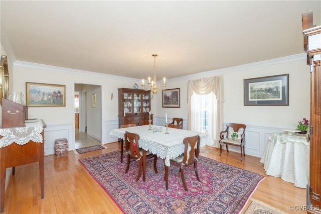 dining space with a chandelier, crown molding, and light wood-style flooring