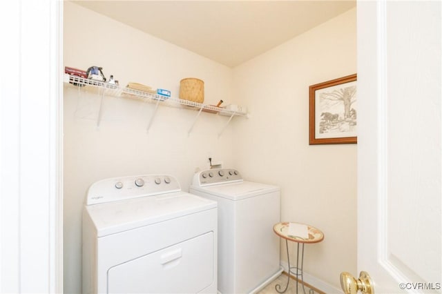 laundry area with laundry area, washing machine and dryer, and baseboards