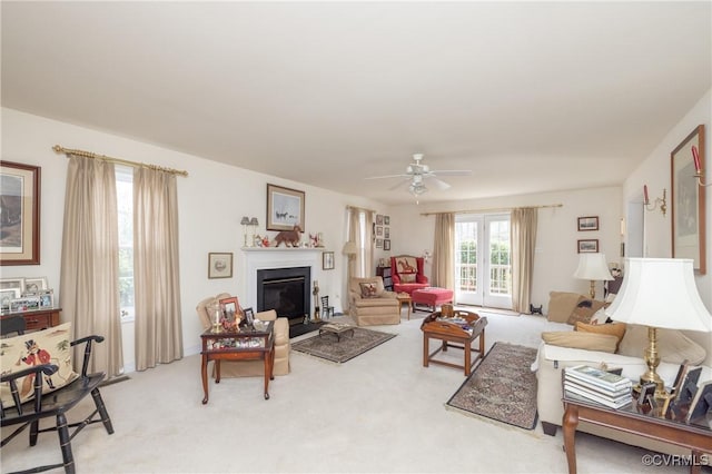 living room featuring ceiling fan, a glass covered fireplace, and light colored carpet