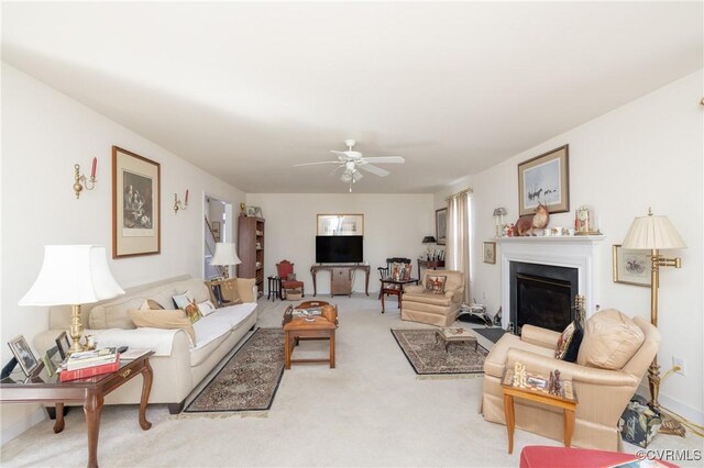 carpeted living area featuring a fireplace with flush hearth and a ceiling fan