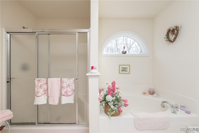 bathroom with a stall shower and a garden tub