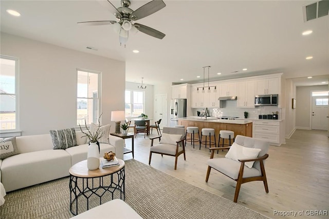 living room featuring light wood-style flooring, visible vents, and recessed lighting