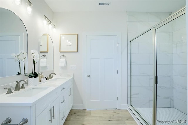 full bathroom featuring a stall shower, visible vents, a sink, and wood finished floors