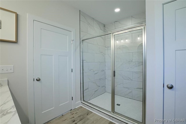 bathroom featuring a stall shower, baseboards, wood finished floors, and recessed lighting