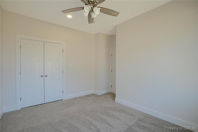 unfurnished bedroom featuring light carpet, ceiling fan, baseboards, and a closet