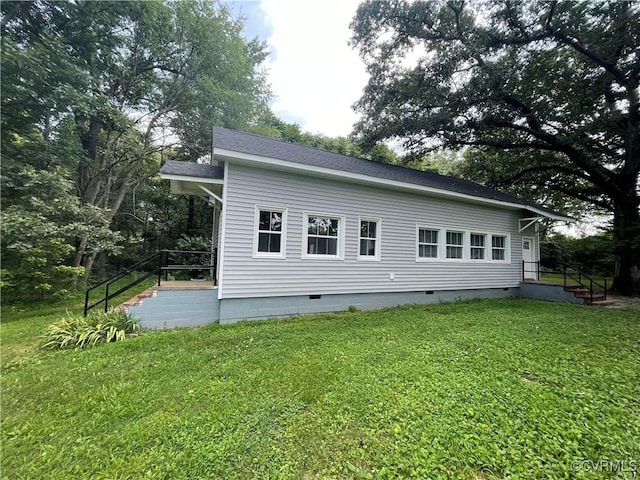 rear view of house with a shingled roof, crawl space, and a lawn