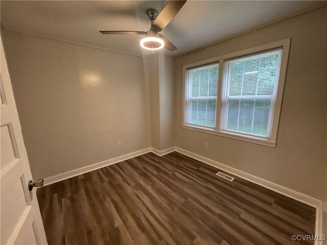 empty room with baseboards, visible vents, dark wood finished floors, and a ceiling fan