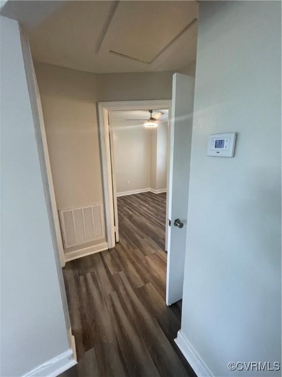 corridor featuring dark wood-style floors, visible vents, and baseboards