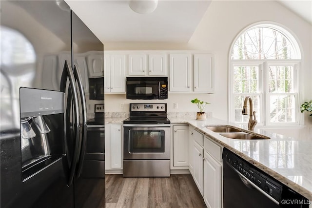 kitchen with dark wood finished floors, white cabinets, a sink, light stone countertops, and black appliances