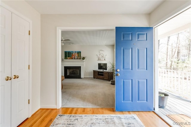 foyer entrance featuring light wood-type flooring, a fireplace, and baseboards