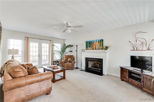 living room featuring french doors, light colored carpet, a fireplace with flush hearth, a ceiling fan, and baseboards