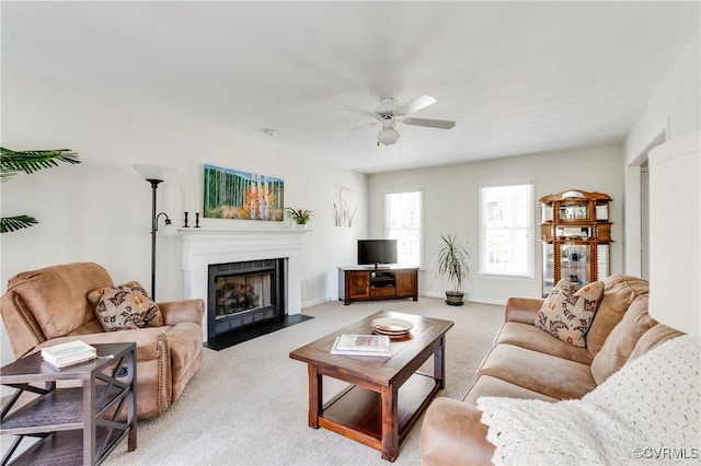 living area with a fireplace with flush hearth, carpet flooring, ceiling fan, and baseboards