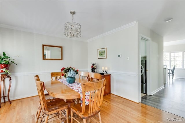 dining space with an inviting chandelier, light wood-style flooring, ornamental molding, and baseboards