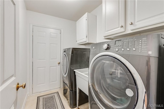 laundry room with cabinet space, washer and clothes dryer, and light tile patterned floors