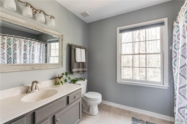 bathroom with baseboards, visible vents, a wealth of natural light, and vanity