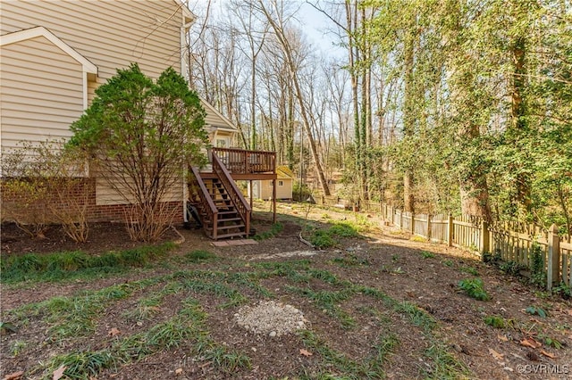 view of yard featuring a deck, stairway, and fence